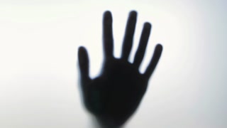 Blurred human hand gradually gaining sharp focus behind frosted panel, creating mysterious shadowy silhouette against pristine white