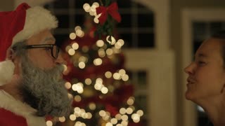 Santa kissing woman under mistletoe