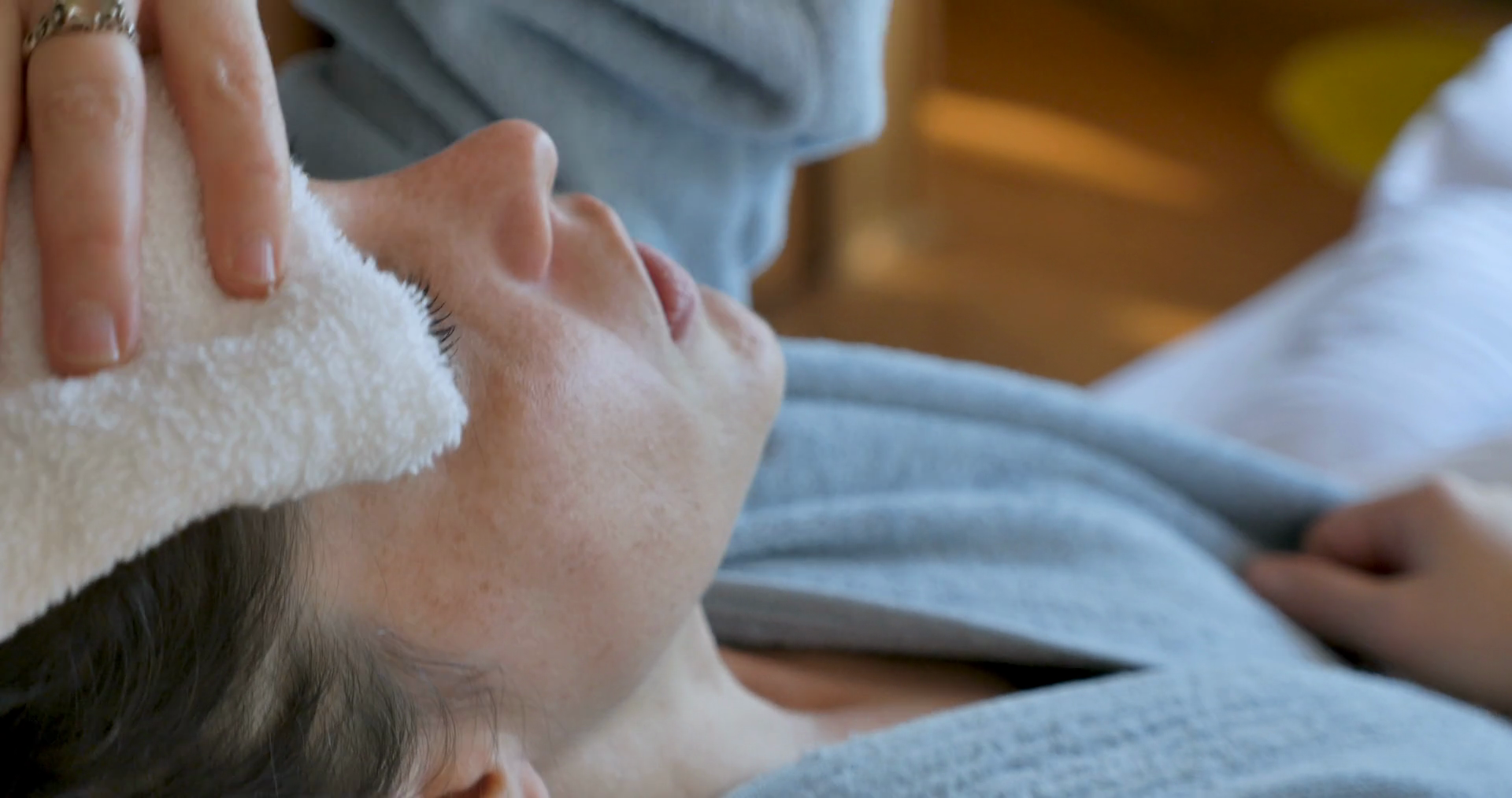 Sick young woman putting a towel on her head to help relieve a fever