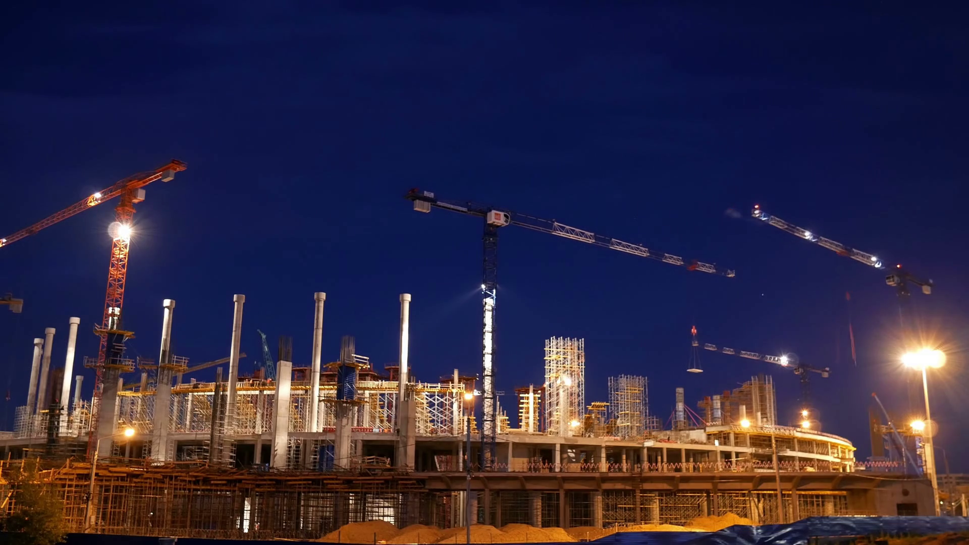 Timelapse with cranes working on construction site on night sky