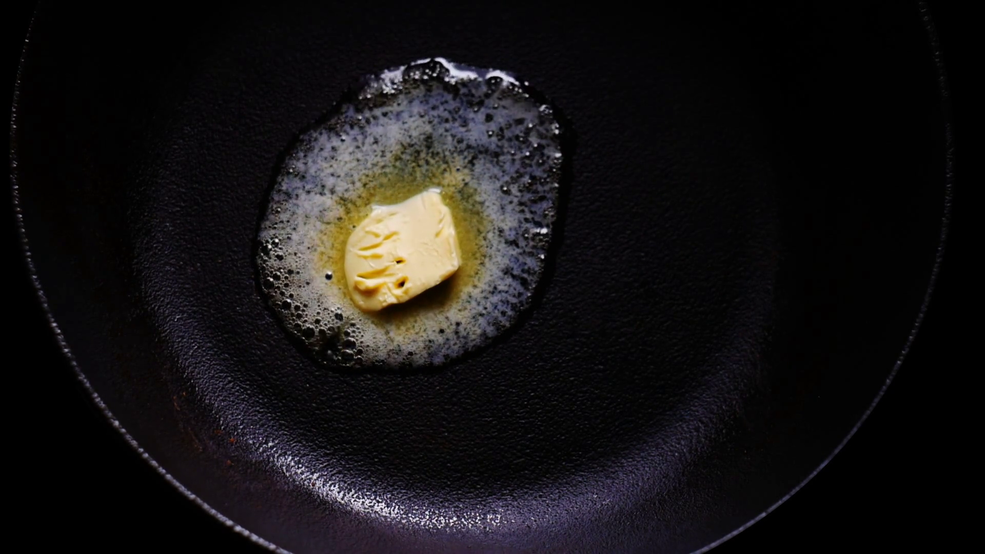 Cube of butter melting pan skillet in slow motion, preparation for