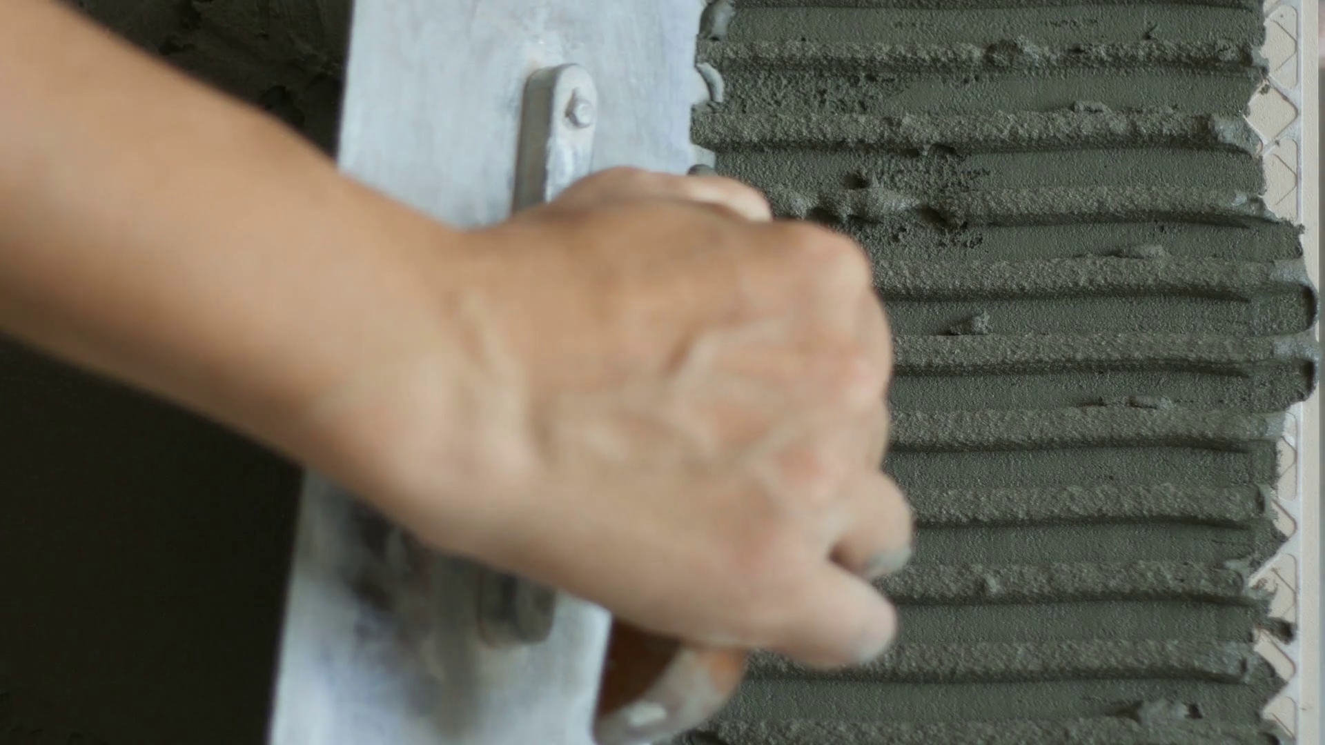 Professional constructor applying cement on floor and laying ceramic