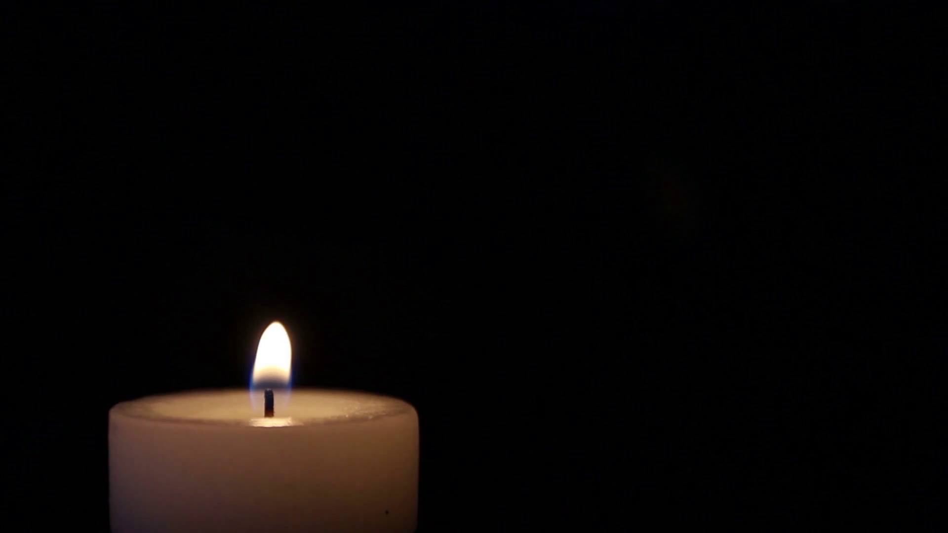 Footage of a candle burning at the left corner, isolated on black