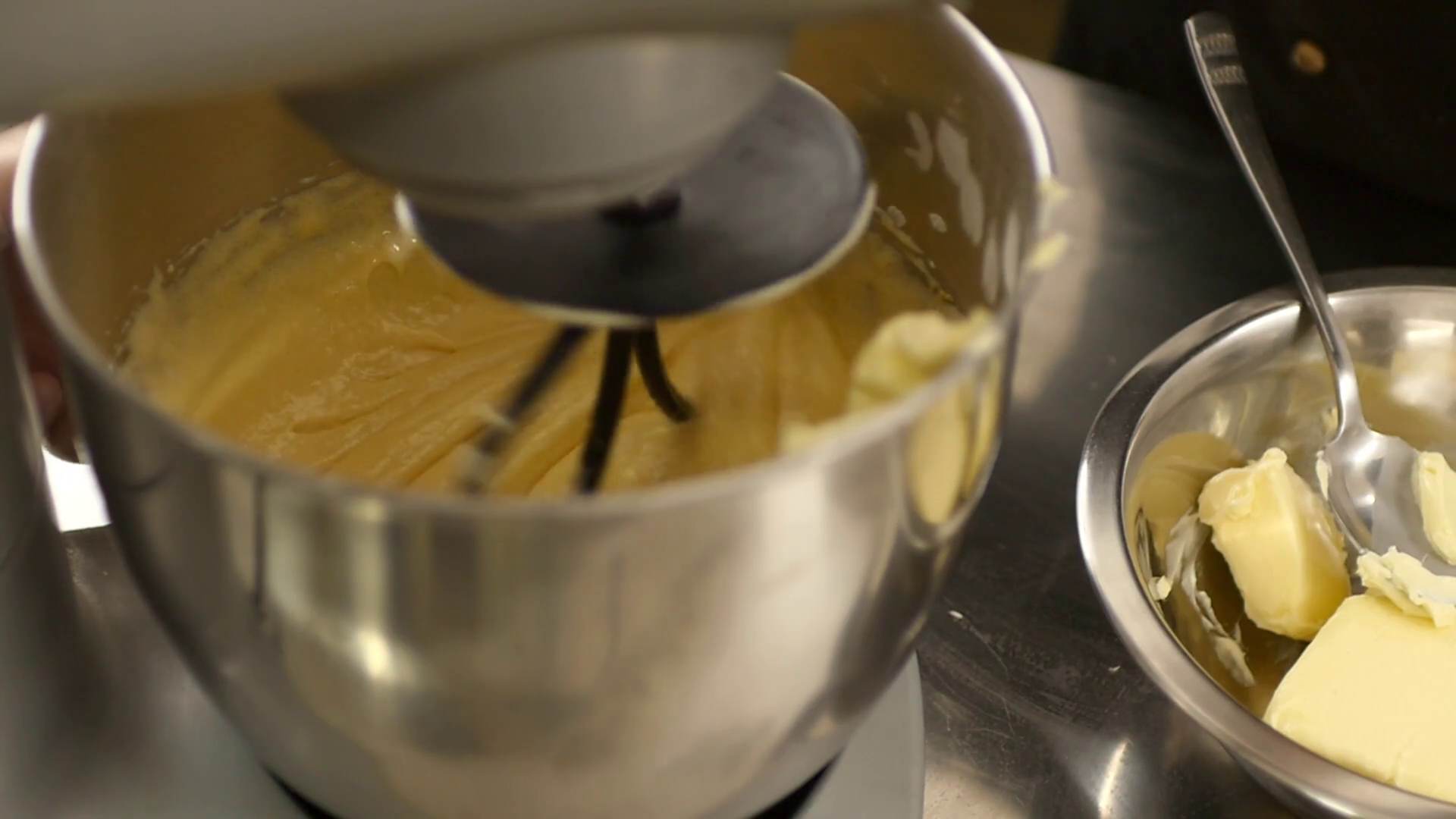 A confectioner adding some butter into a bowl with a mixer... Stock