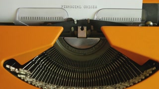 High angle footage of a person writing FINANCIAL CRISIS on an old typewriter, with sound