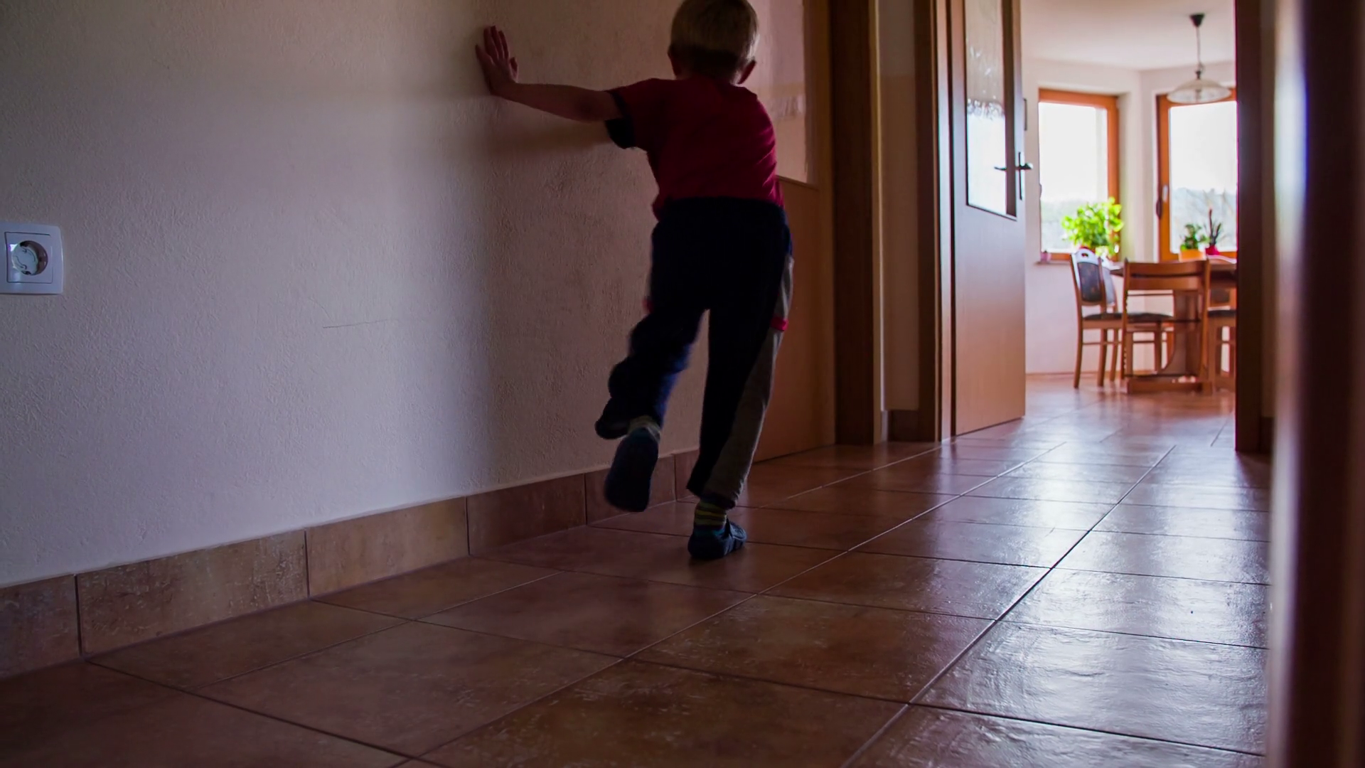 Kid crashing in to wall running to another room in slow motion. Wide