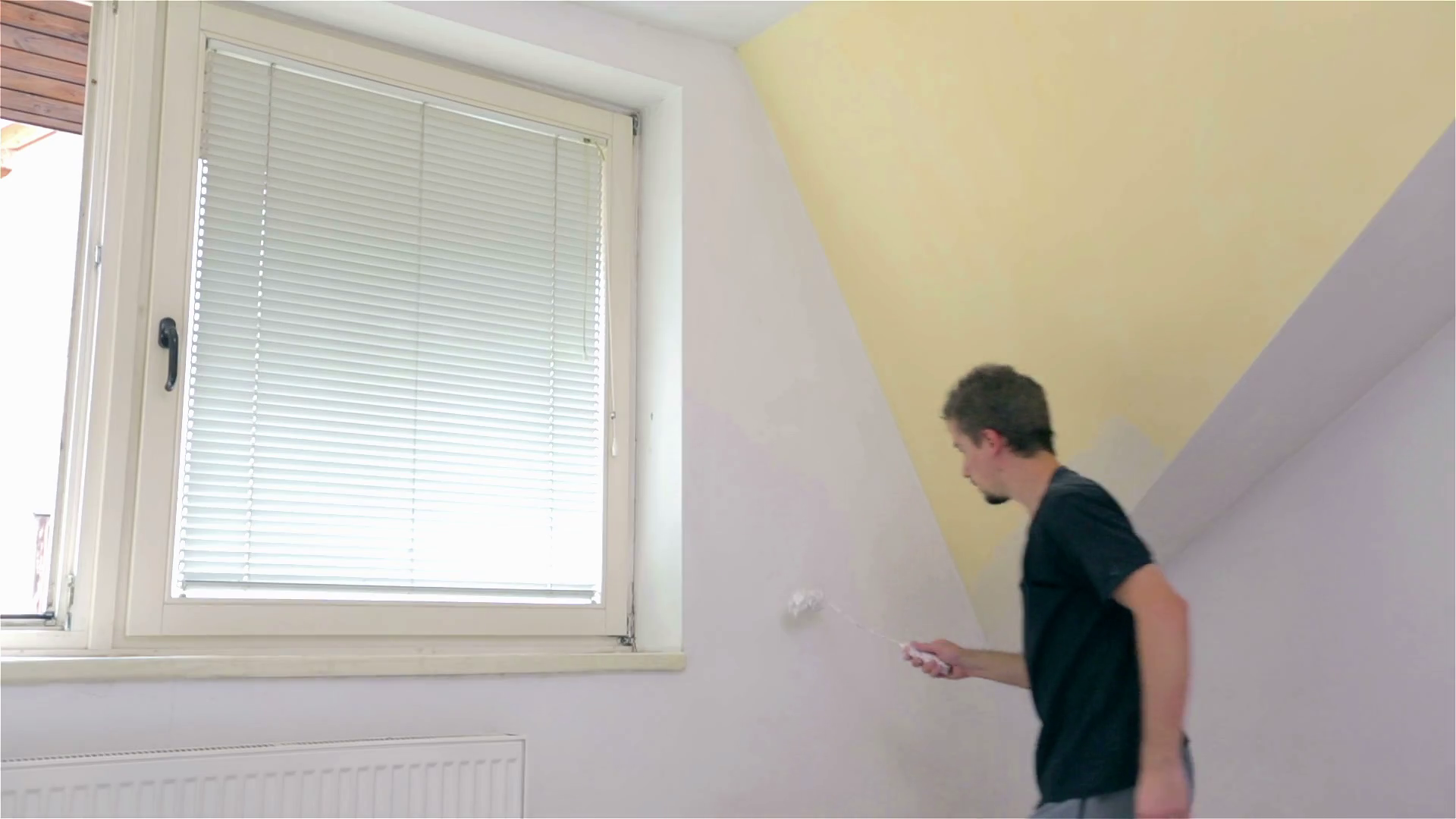Male painting walls around windows. Young man in new apartment painting