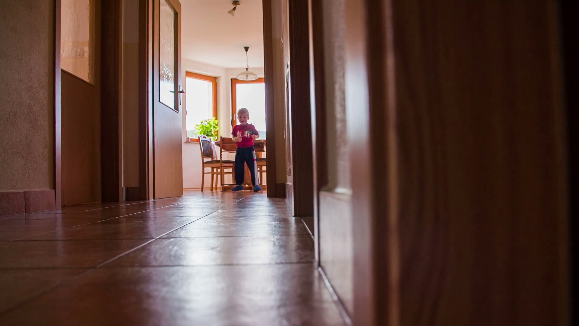 Running up and down the hallway at home. Low angle slow motion shot of young kid at own home