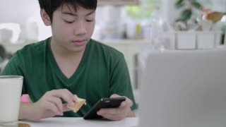 Young boy using smartphone apps while enjoying a healthy breakfast at home