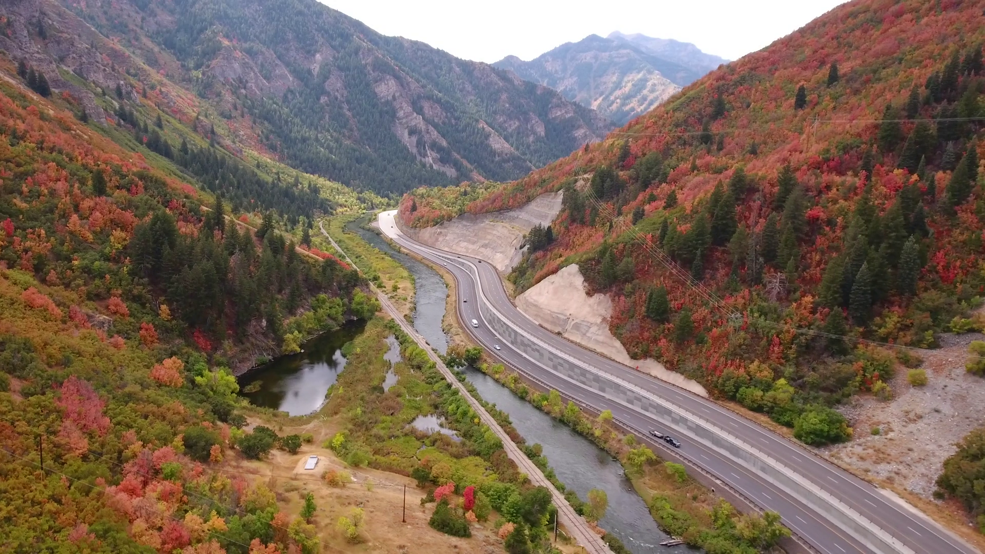 Aerial shot of cars driving on mountain highway with fall colors Stock