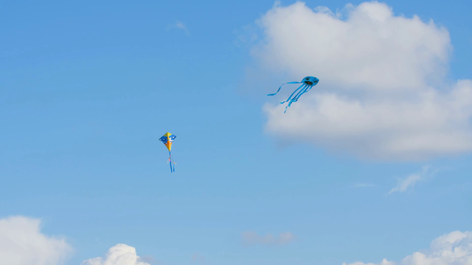 Two colourful kites flying in blue sky with clouds Stock Video Footage 0015 SBV338662175