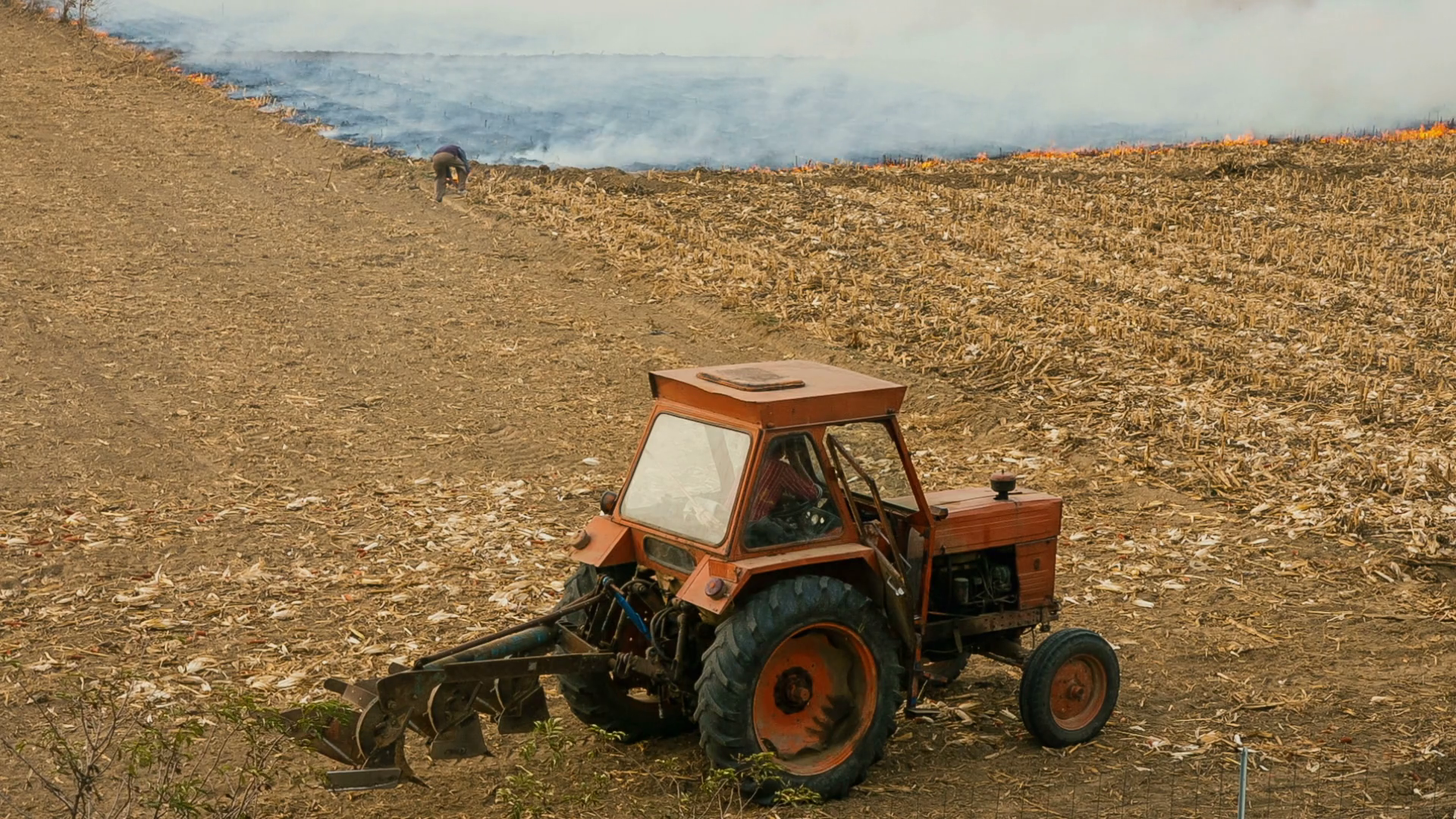 Vintage tractor and man burning weeds on agricultural field Stock Video