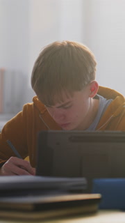 Close Up of Focused Young Man Working on Tablet in Classroom, Surrounded by Classmates. Boys Discussing Educational Project. Concept Modern