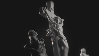 Cinematic View of Grieving Figure Statue Looking Up and Praying to Jesus Christ on Cross, Highlighted by Dramatic Light in Darkness