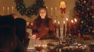 Young girl shares holiday joy with diverse family at warm Christmas dinner