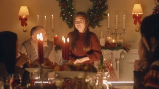 Young girl shares holiday joy with diverse family at warm Christmas dinner
