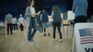Queue of multi ethnic American citizens come to vote in polling station. Vote here sign on the floor. National Election Day in United States