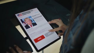 ZAPORIZHYA, UKRAINE -MARCH 15, 2024: Close up of female voter making choice and voting for Joe Biden in voting booth using tablet computer