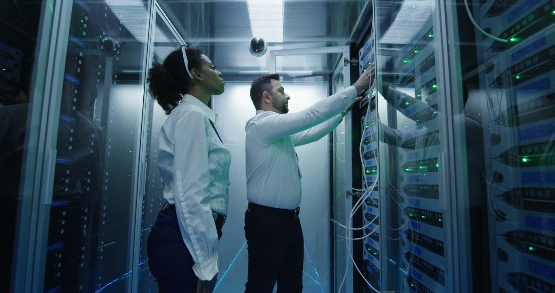 Medium shot of two diverse employees working in a data center server