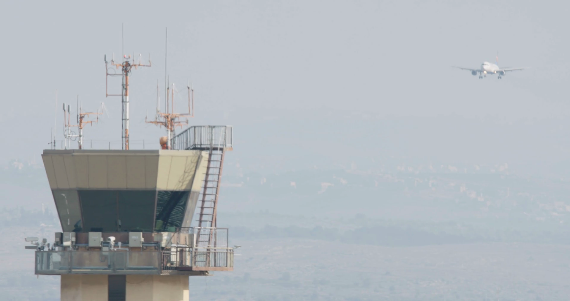 Airport control tower with airplane landing in the background Stock