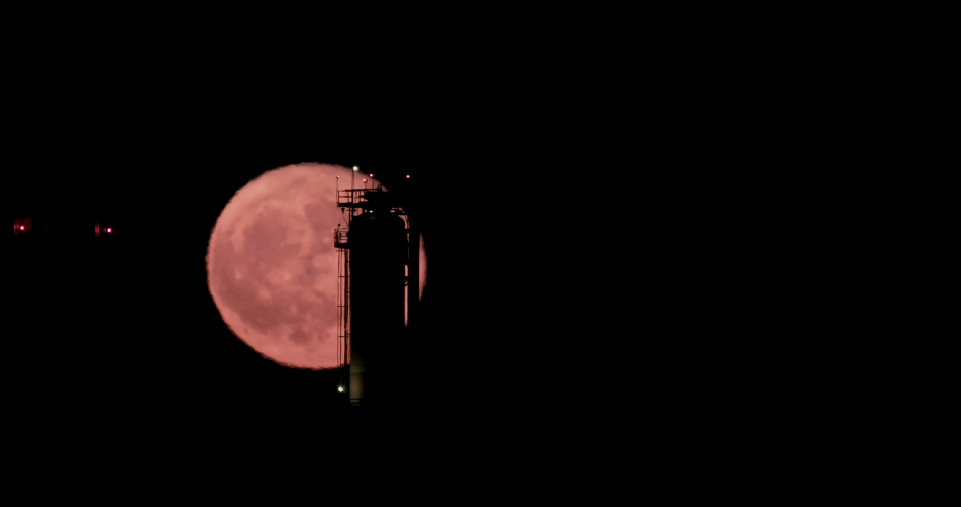Red full moon rising from behind a large oil refinery Stock Video ...