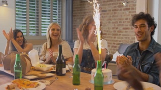Multi-cultural group of friends celebrating man's birthday at home with spectacular firework cake and singing happy birthday - shot in slow motion