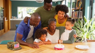 Multi-Generation Family With Military Father Celebrating Grandmother's Birthday With Cake At Home