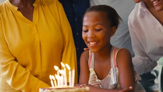 Multi-Generation Family Celebrating Granddaughter's Birthday With Cake And Candles At Home