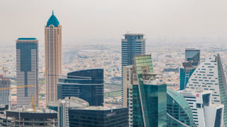 Dubai's business bay towers before sunset timelapse. Rooftop view of some skyscrapers and new towers under construction.