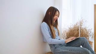 Young woman working from home. Happy individual using laptop in living room.