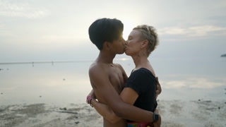 Hugging Couple with Age Differences Kissing on a Beach and an Look at Camera at Seaside Sunset Face (Stock Footage)