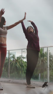 Two Asian Women Practicing Yoga Outdoors on a Rooftop
