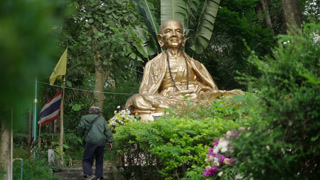 Unrecognizable Man Walking Next to Buddha Statue in Bubhing Palace Thailand