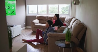 Happy Gay Couple Watching Sports Game On TV At Home