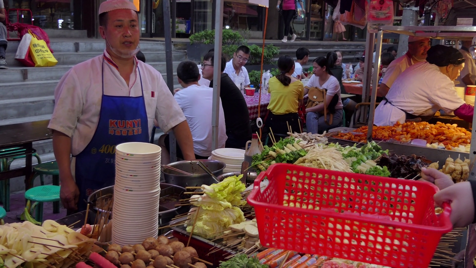Woman buying food at stall in Zhengning Road, night market, food street in Lanzhou, Gansu