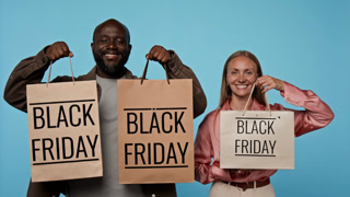Portrait of smiling African American man and Caucasian woman raising Black Friday shopping bags. Video suited for retail sales promotions, discount advertising and marketing campaigns