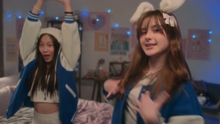 Multi-ethnic teenage girls in blue and white bomber jackets dancing to k-pop music and lip syncing for camera at home