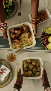Vertical top down shot of hands of anonymous African American couple putting dishes on holiday table getting ready for Kwanzaa festival