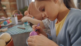 Close-up shot of adorable child drawing on Easter-themed table with marker pen