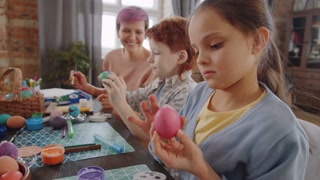 Child creating Easter egg art with family at home