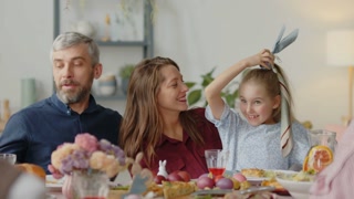 Happy child and parents enjoying Easter egg hunt at family dinner