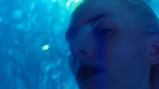 Close-up portrait of young woman with unique makeup and special effects in studio with neon lights