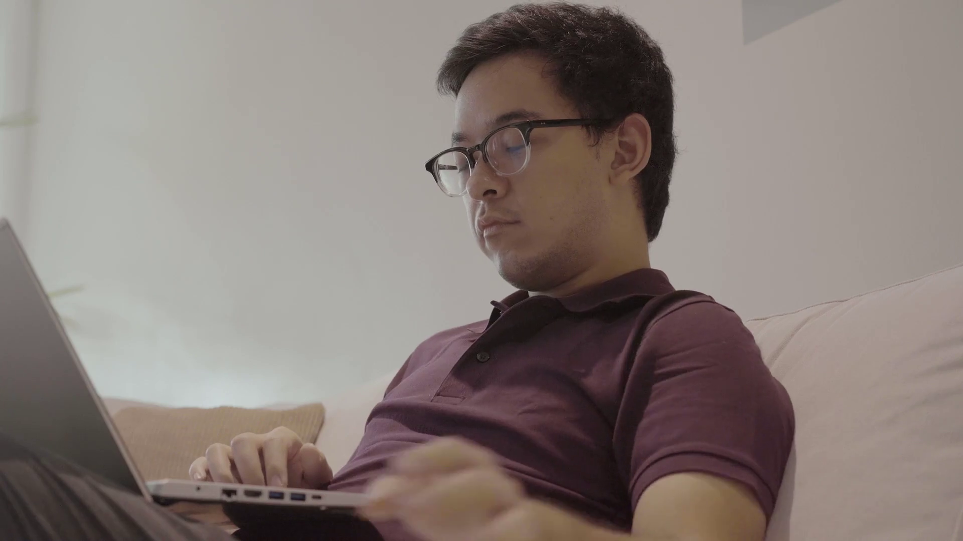Tired Filipino man reads notes while working in living room at home