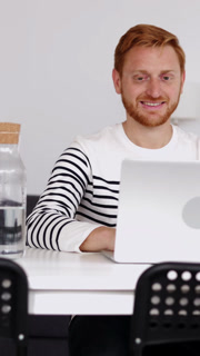 Young student man working on laptop computer sitting on table at home