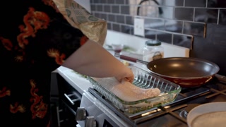 Handheld shot of fish fillet placed into glass baking pan