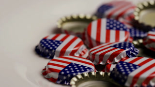 Macro shot of pile of metal bottle caps with American flag print rotating on white background patriotic drinking symbol celebration concept