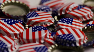 Pile of metal bottle caps with American flag print rotating representing patriotism and independence day celebration events and united states national holiday concepts