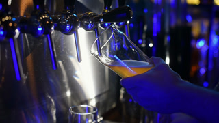 Bartender pouring beer into glass with bubbles close up
