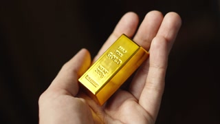 https://dm0qx8t0i9gc9.cloudfront.net/thumbnails/video/rMadI-Zz9l0vd44f0/videoblocks-investor-holding-gold-bar-safe-investment-concept_boigmzbcex_thumbnail-180_04.jpg