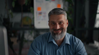Senior business man working at computer and smiling to the camera at contemporary office